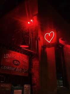 a red neon sign on the side of a brick building with a heart above it