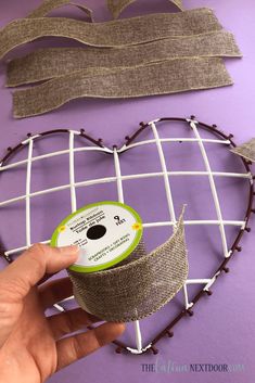 someone is holding a spool of tape in front of a heart shaped wire rack