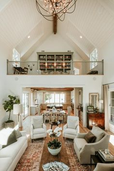 a living room filled with lots of furniture and a chandelier hanging from the ceiling