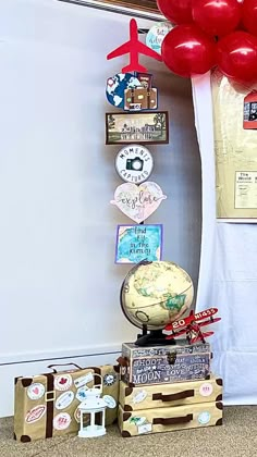 there is a globe and balloons on top of suitcases in front of a white wall