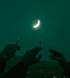 two people holding matches in their hands with the moon above them and city lights behind them