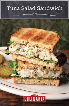 the tuna salad sandwich is stacked on top of bread with lettuce and olives