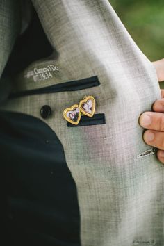 a person wearing a suit and tie with two hearts on the lapel, while holding his hand in his pocket