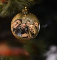 an ornament hanging from a christmas tree with two people in it and one person holding