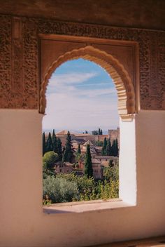 an arched window overlooking a city with trees and buildings