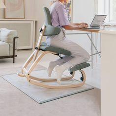 a man sitting at a desk using a laptop computer and standing on a rocking chair