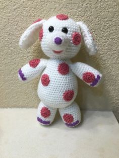 a crocheted stuffed animal sitting on top of a white table next to a wall