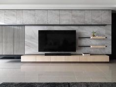 a modern living room with a large tv on the wall and shelving units in front of it