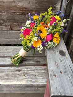 a bouquet of flowers sitting on top of a wooden bench