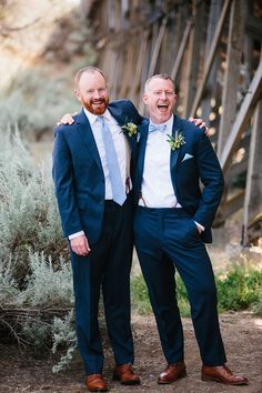 two men standing next to each other in suits