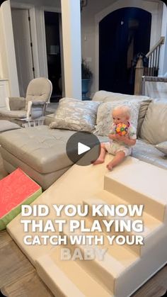 a baby sitting on top of a couch in a living room next to a stair case