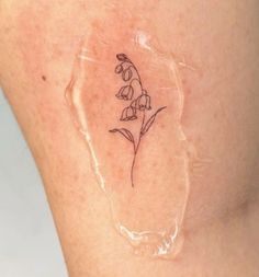 a small tattoo on the back of a woman's thigh, with a flower in it