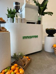 there are oranges and pineapples in baskets next to the juicer on the counter