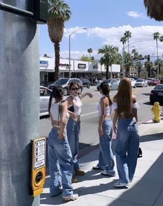 four women are standing on the side walk talking to each other and pointing at something