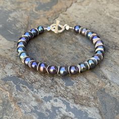 This stunning pearl bracelet features beautiful round peacock pearls. They are iridescent purple, blue and green freshwater pearls. Each one is separated with a sterling silver wavy disk. Finished with a sterling silver, Hill Tribe toggle clasp. 7.5 inch Bracelet Pearl alone: 6.5mm To see more from East Village Jewelry~ http://eastvillagejewelry.etsy.com All orders ship out within 24 hours, excluding holidays and Sundays Feel free to contact me with any questions. Use coupon code VILLAGE14 for 10% off all orders over $200.00 THIS ITEM WILL SHIP OUT WITHIN 24 HOURS OF ORDERING FREE SHIPPING WITHIN THE UNITED STATES! Elegant Iridescent Round Bead Bracelets, Sunday Feels, Peacock Pearls, Peacock Pearl, Iridescent Purple, Bracelet Pearl, East Village, Toggle Clasp, Pearl Bracelet