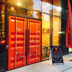 an orange shipping container sitting in front of a building with a sign next to it