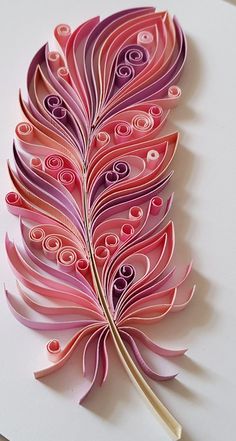 an intricately designed paper art piece with pink and purple feathers on white paper background