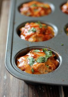 a muffin tin filled with lots of different types of food on top of a wooden table