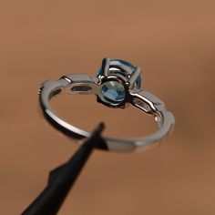 It is a Swiss blue topaz ring. The main stone is 7mm*7mm round cut, weight about 1.66 carats. The basic metal is sterling silver and plated with rhodium. To change the metal to a solid gold (white/rose) or platinum is also available, please ask for a quotation if you want. You can also go to my shop Home for more elegant rings: https://www.etsy.com/shop/godjewelry?ref=hdr_shop_menu Topaz is November birthstone. More topaz rings: https://www.etsy.com/shop/godjewelry?ref=hdr_shop_menu&section_ Topaz Ring With Round Stone, Silver Topaz Crystal Ring With Prong Setting, Topaz Ring With Center Stone, Blue Topaz Solitaire Promise Ring, Topaz Birthstone Ring With Accent Stones, Brilliant Round Cut Topaz Birthstone Ring, Classic Blue Topaz Ring With Round Band, Round Cut Topaz Birthstone Ring With Accent Stones, Topaz Crystal Ring With Center Stone