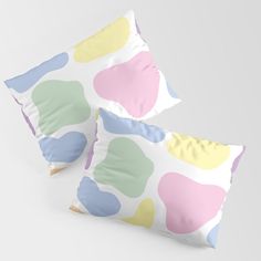 two pillows with colorful shapes on them sitting side by side in front of a white background