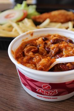 a close up of a bowl of food on a table with fries and coleslaw