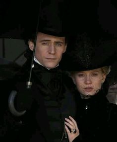 a man and woman dressed in black under an umbrella