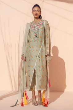 This celadon-colored khaddi silk kurta is printed with embroidered birds and foliage on the neckline that transform this piece into a muted wardrobe work of art. The co-ord printed trousers and colorful tassels hanging from the chiffon dupatta add a playful feel to the piece. Spring Anarkali Set In Cotton Silk With Traditional Drape, Festive Green Kurta With Tassels, Bohemian Set With Sheer Dupatta In Cotton Silk, Bohemian Cotton Silk Set With Sheer Dupatta, Bohemian Georgette Kurta With Sheer Dupatta, Traditional Anarkali Set With Tassels For Designer Wear, Unstitched Bohemian Kurta With Sheer Dupatta, Spring Kurta With Dupatta In Traditional Drape, Designer Wear Anarkali Set With Tassels