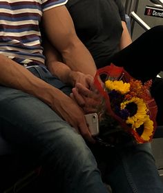 a man sitting on a bus holding a bouquet of flowers and a cell phone in his hand