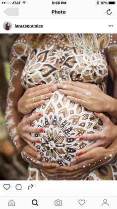 the pregnant woman is holding her belly covered in white and brown designs on her body