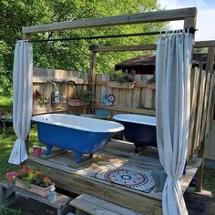 a blue bath tub sitting on top of a wooden deck next to a white curtain