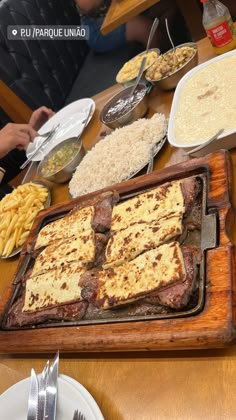 a wooden table topped with different types of food and silverware on top of it