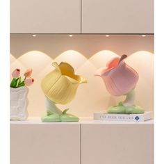 three ceramic vases sitting on top of a shelf next to each other with flowers in them