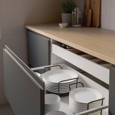 an open drawer in a kitchen filled with plates and bowls on top of a counter