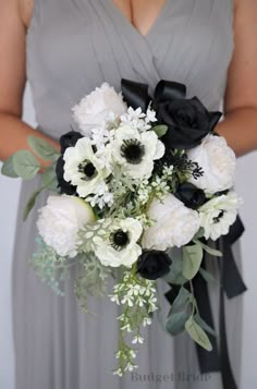 a bridesmaid holding a bouquet of white and black flowers