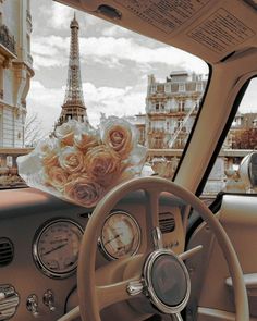 a car dashboard with the eiffel tower in the background and flowers on the dash board