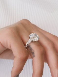 a close up of a person's hand with a diamond ring on their finger