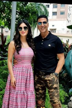 a man and woman standing next to each other in front of some plants with flowers