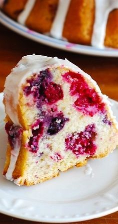 a piece of cake with white frosting and raspberry topping on a plate