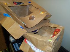 three brown paper bags are stacked on top of each other, with stickers all over them