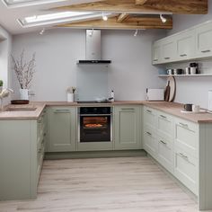 a kitchen with green cabinets and an oven in the center is seen from across the room