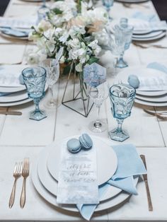 the table is set with blue and white plates, silverware, and flowers in vases