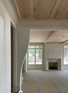 an empty room with blue tape on the floor and two windows in the back ground