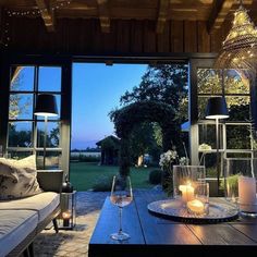 a table with candles and wine glasses on it in front of an open patio door