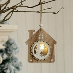 a wooden ornament hanging from a tree with a lit candle in the shape of a house