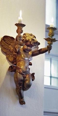 a statue of an angel holding a candle on a wall next to a brick wall