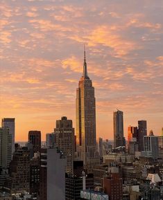 the city skyline is lit up at sunset, with skyscrapers in the foreground