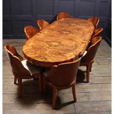 a large wooden table with chairs around it on a hard wood floored area next to a wall