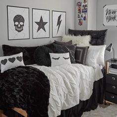 a bedroom with black and white bedding, skulls on the wall and pictures above it