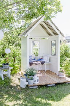 a small white shed sitting on top of a lush green field next to a wooden deck