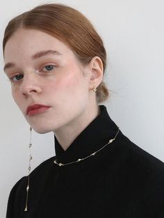 a woman with red hair wearing a black shirt and gold chain necklace on her neck